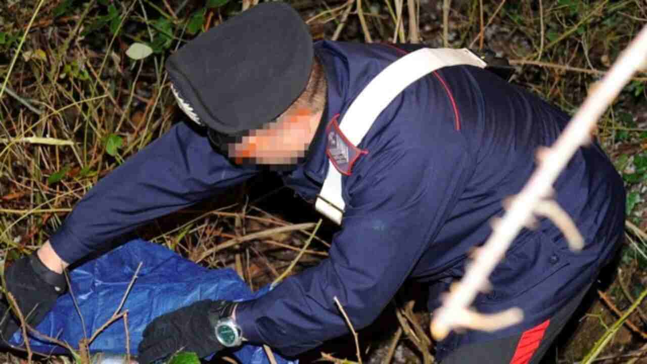 Un carabiniere mentre lavora vicino a un cadavere