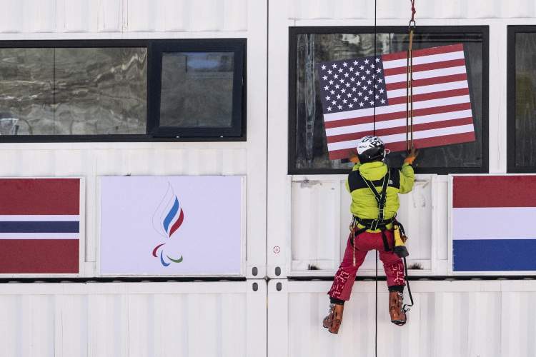 Un operaio mentre posiziona la bandiera degli States per le Paralimpiadi di Pechino