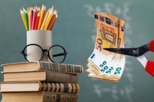 Libri scolastici e forbici che tagliano soldi