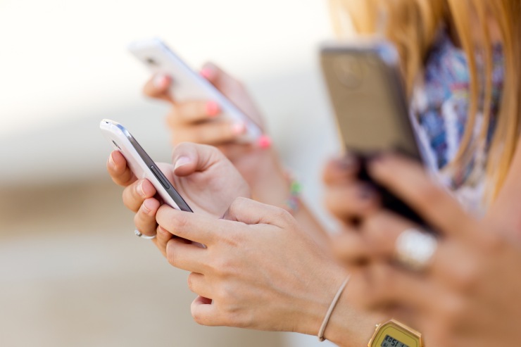 Ragazzi con smartphone in mano che chattano su WhatsApp