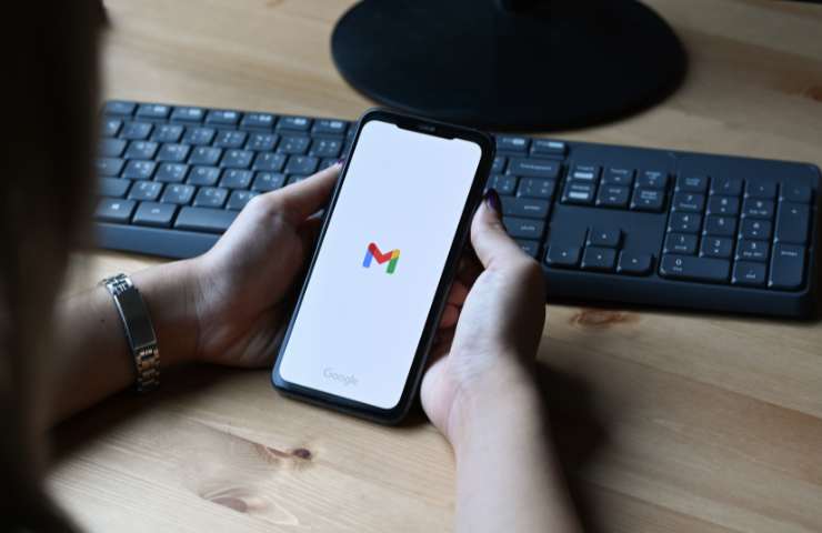 smartphone tra le mani e logo gmail