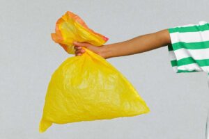 Una mano che tiene una busta gialla dell'immondizia