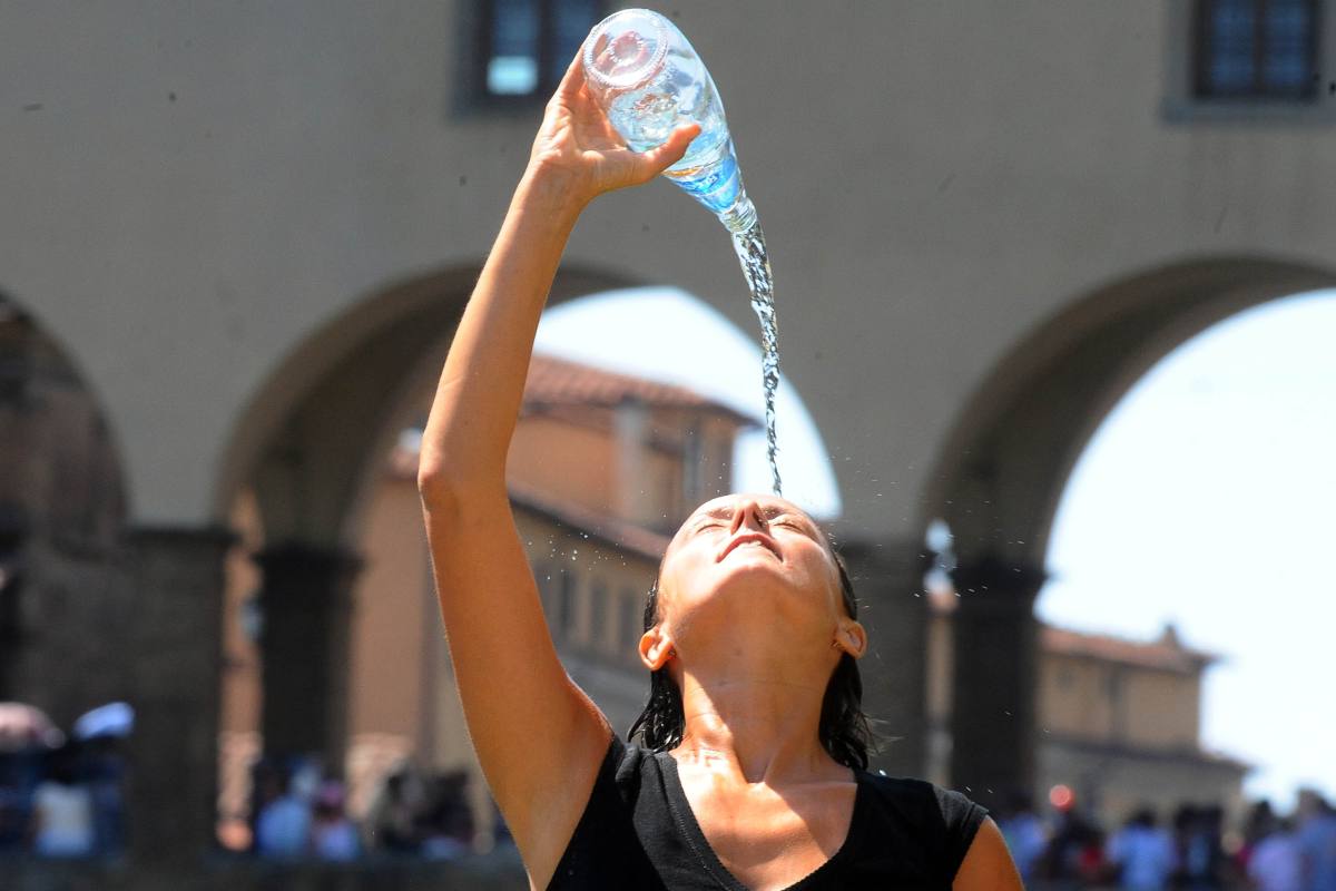 Una turista si rinfresca bagnandosi la testa con l'acqua