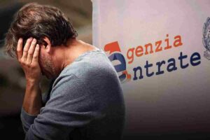 persona con le mani sul volto e dietro insegna Agenzia Entrate