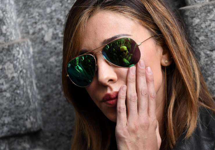Belen Rodriguez con gli occhiali da sole e una mano sulla guancia