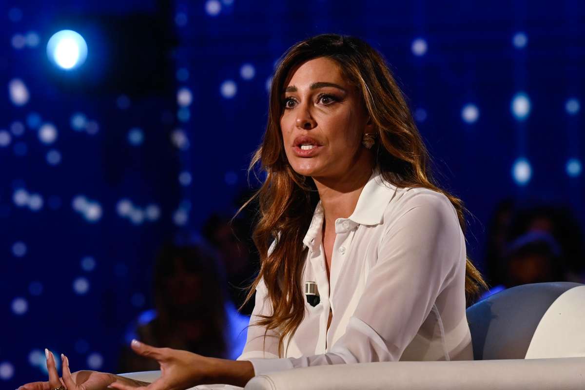 Belen Rodriguez seduta con una camicia bianca durante un'intervista