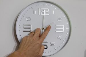 Una mano che rettifica l'orario segnato dalle lancette dell'orologio