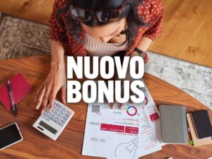 scritta nuovo bonus con dietro fogli e calcolatrice su una scrivania