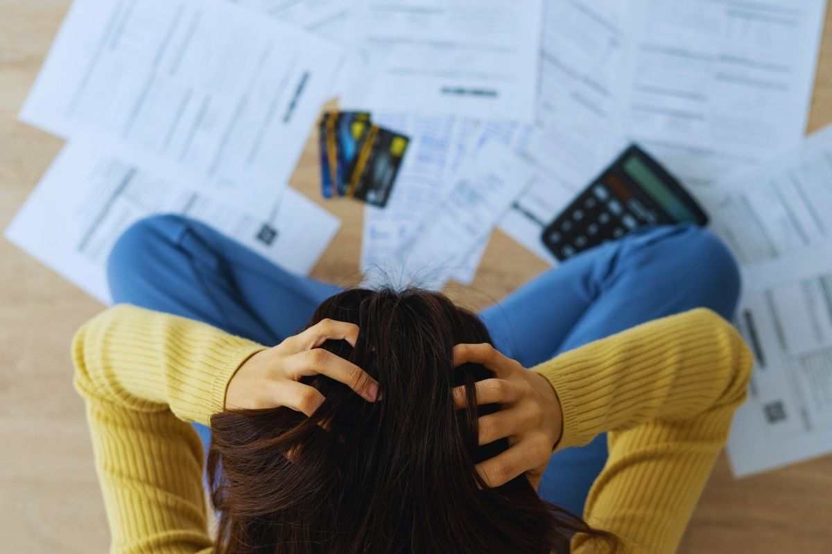 ragazza si mette le mani in testa mentre fa i conti