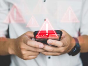 segnale di pericolo con dietro una persona che utilizza uno smartphone