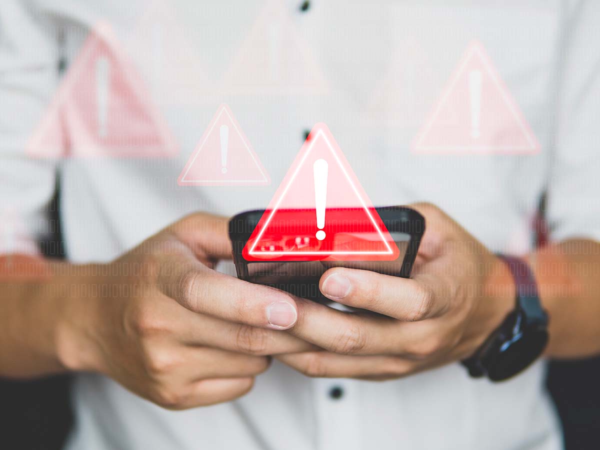 segnale di pericolo con dietro una persona che utilizza uno smartphone