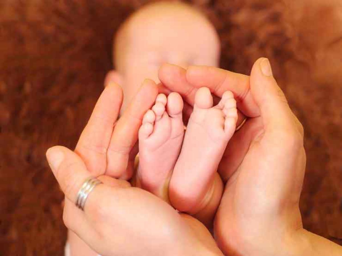 Una donna accarezza i piedini della sua bimba neonata