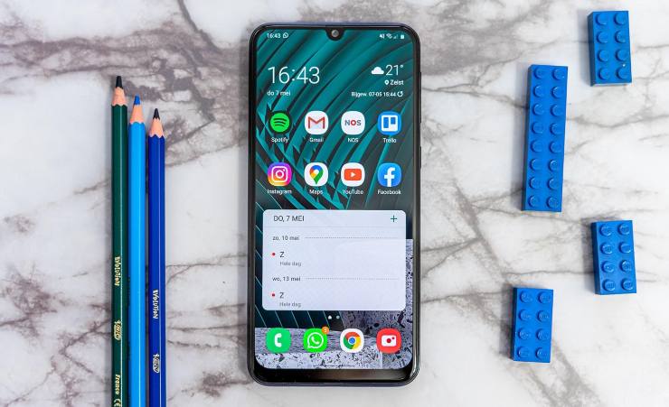 Schermata principale di uno smartphone con accanto matite e pezzi di lego