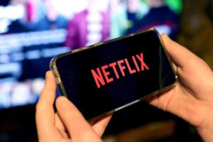 Smartphone in mano su schermata Netflix
